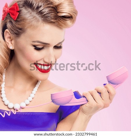 Image of beautiful woman with phone dressed in pin up style, isolated over pink background. Female blond girl posing in retro fashion and vintage studio concept. Square.