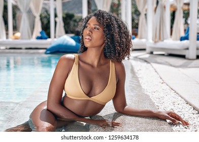  image of beautiful young afro american woman in beige swimwear lying near the swimming pool outdoors. Photo of Bayleigh Dayton - Miss Missouri 2017