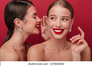 Image Of A Beautiful Young Cheery Positive Two Women With Bright Red Lipstick Isolated Over Red Wall Background Talking With Each Other Gossiping.