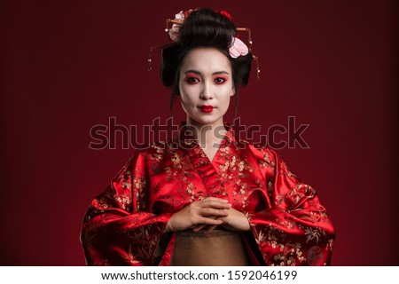 Image of beautiful young geisha woman in traditional japanese kimono isolated over red background