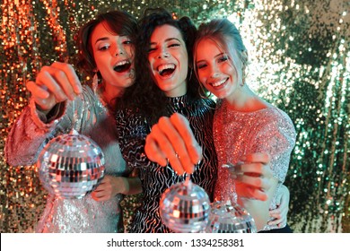 Image Of A Beautiful Young Happy Women Friends Posing Over Glitter Wall Background Holding Little Mini Toys Disco Balls.