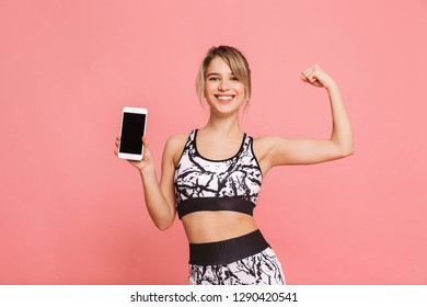 Image Of A Beautiful Young Sports Blonde Woman Make Fitness Exercises Isolated Using Mobile Phone Showing Biceps.