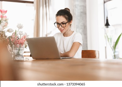 Image of a beautiful young student girl sitting indoors using laptop computer.