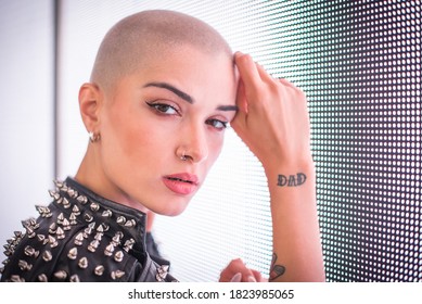 Image Of A Beautiful Young Woman Posing Against A Led Panel. Shaved Head Teenager With Alternative Look Making Urban Portraits