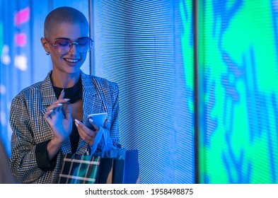 Image Of A Beautiful Young Woman Posing Against A Led Panel. Shaved Head Teenager With Alternative Look Making Urban Portraits