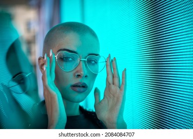 Image Of A Beautiful Young Woman Posing Against A Led Panel. Shaved Head Teenager With Alternative Look Making Urban Portraits