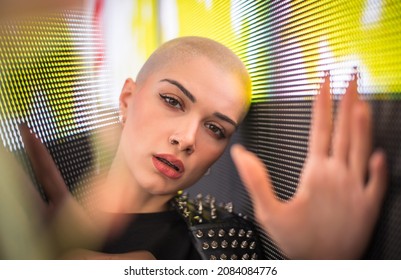 Image Of A Beautiful Young Woman Posing Against A Led Panel. Shaved Head Teenager With Alternative Look Making Urban Portraits