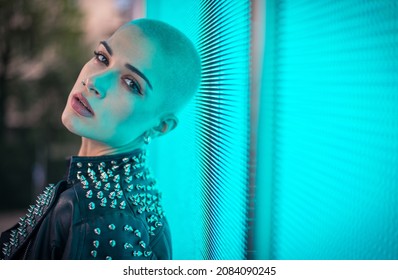 Image Of A Beautiful Young Woman Posing Against A Led Panel. Shaved Head Teenager With Alternative Look Making Urban Portraits