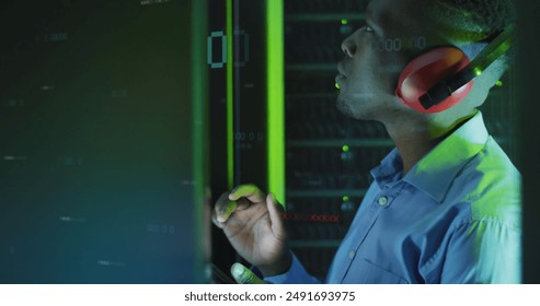 Image of binary coding over african american male engineer using digital tablet at server room. Computer interface and business data storage technology concept