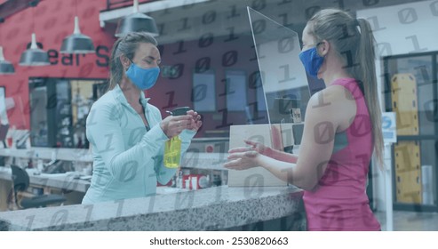 Image of binary coding over caucasian female worker with face mask disinfecting hands. social media and communication interface during covid 19 pandemic concept digitally generated image. - Powered by Shutterstock