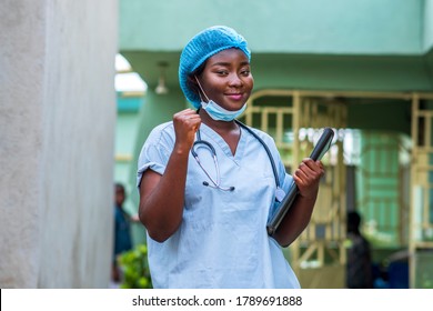 image of a black health professional wearing face mask under chin and stethoscope around neck,hands raised up for support and strength in covid-19 pandemic