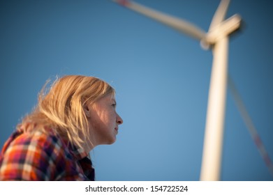 An image of blonde girl and windturbine in the background