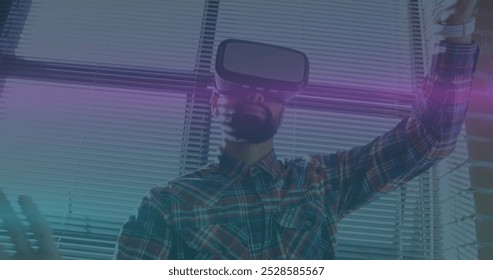 Image of blue and pink light trails moving over biracial man wearing vr headset at office. Futuristic business technology concept - Powered by Shutterstock