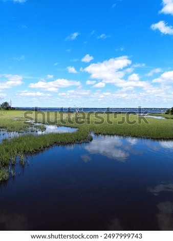 Image of a blue sky with clouds overlooking a wetlands. Inlet in background. Taken in Pine Knoll Shores, NC.