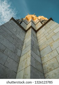 Image of bottom up view along a wall of a tower with golden top