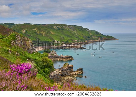 Image of Bouley Bay from adjacent cliff paths. with cloudy sky and calm sea. Jersey, Channel Islands. Selective focus.