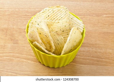 Image Of A Bowl Of Sour Cream And Onion Flavored Potato Chips On A Wooden Table