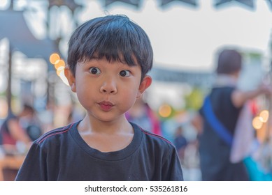 image of boy in black T-shirt with blur festival light in background.
