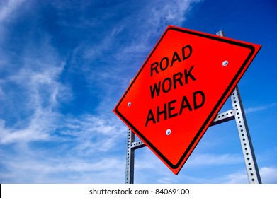 Image bright orange road work ahead sign against blue sky and light clouds