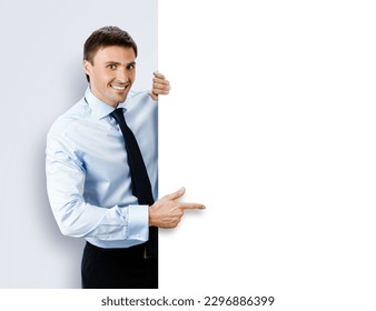 Image of business man, employee, professional in confident shirt wear. Businessman stand behind, hang over, show point finger empty white banner signboard. Isolated grey gray background - Powered by Shutterstock