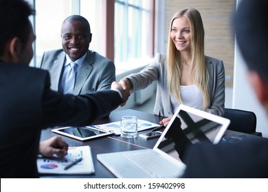 Image of business partners handshaking on background of their colleague