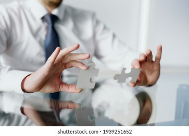 Image of businessman connecting elements of white puzzle.