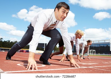 Image of businessman getting ready for race with two females on background - Powered by Shutterstock