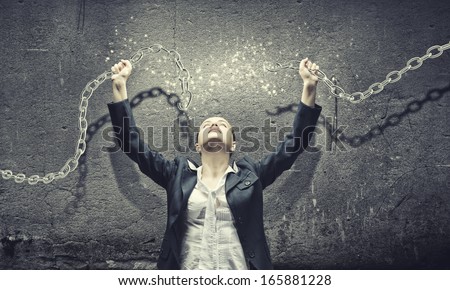Image of businesswoman in anger breaking metal chain