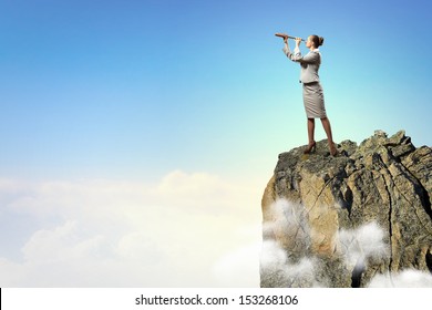 Image of businesswoman looking in telescope standing atop of rock