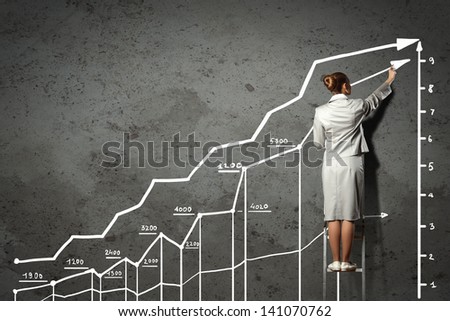 Image of businesswoman standing on ladder and drawing on wall