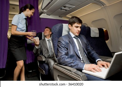 Image Of Busy Male Typing On Laptop With Pretty Stewardess Giving Glass Of Water To Successful Businessman On Background