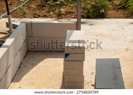 image captures assembly of blockwork in an urban construction site under bright daylight.