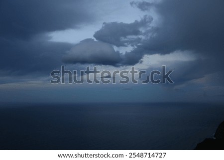 The image captures a dramatic and contrasting moment in the sky. Dark, dense clouds, heavy with rain, dominate most of the scene, creating a gloomy and stormy atmosphere. However, a beam of light filt