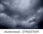 The image captures a dramatic expanse of sky dominated by towering storm clouds. Thick, heavy masses of dark gray and charcoal clouds loom from both sides of the frame, curving inward as if closing around a brighter opening at the center. The clouds appear dense and textured, with soft, billowing edges that suggest constant movement and turbulence. Their forms are layered and sculpted, with deeper shadows pooling in the folds and lighter grays tracing the contours where faint light filters through.
At the center of the composition, a pale, diffused glow breaks through the gloom. This lighter patch of sky, almost silvery in tone, creates a striking contrast against the surrounding darkness. It feels like a temporary clearing, a narrow corridor of light between two advancing walls of cloud. The brightness does not come from direct sunlight but rather from sunlight obscured by thick vapor, giving the scene a moody, atmospheric quality.
The left side of the image shows clouds with slightly more variation in tone, where subtle gradations of gray transition from smoky light to near-black. The right side appears heavier and darker, with a more imposing, shadowed presence. The cloud formations rise upward and inward, giving the impression of height and scale, as though the viewer is looking up from the ground at a vast, shifting ceiling of weather.
There are no visible landmarks, buildings, or horizon lines—only sky. This absence of grounding elements enhances the feeling of immersion, as if the viewer is enveloped by the storm. The image conveys tension and anticipation, suggesting that rain or thunder may soon follow. At the same time, the central glow hints at resilience and contrast—light pushing gently against encroaching darkness. The overall mood is powerful, contemplative, and slightly ominous, capturing the raw, ever-changing drama of the atmosphere.