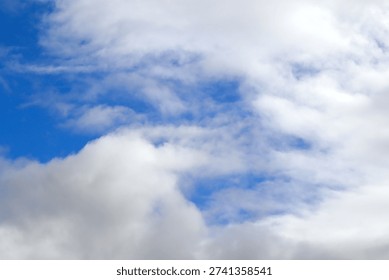 The image captures a dramatic expanse of sky dominated by towering storm clouds. Thick, heavy masses of dark gray and charcoal clouds loom from both sides of the frame, curving inward as if closing around a brighter opening at the center. The clouds appear dense and textured, with soft, billowing edges that suggest constant movement and turbulence. Their forms are layered and sculpted, with deeper shadows pooling in the folds and lighter grays tracing the contours where faint light filters through.
At the center of the composition, a pale, diffused glow breaks through the gloom. This lighter patch of sky, almost silvery in tone, creates a striking contrast against the surrounding darkness. It feels like a temporary clearing, a narrow corridor of light between two advancing walls of cloud. The brightness does not come from direct sunlight but rather from sunlight obscured by thick vapor, giving the scene a moody, atmospheric quality.
The left side of the image shows clouds with slightly more variation in tone, where subtle gradations of gray transition from smoky light to near-black. The right side appears heavier and darker, with a more imposing, shadowed presence. The cloud formations rise upward and inward, giving the impression of height and scale, as though the viewer is looking up from the ground at a vast, shifting ceiling of weather.
There are no visible landmarks, buildings, or horizon lines—only sky. This absence of grounding elements enhances the feeling of immersion, as if the viewer is enveloped by the storm. The image conveys tension and anticipation, suggesting that rain or thunder may soon follow. At the same time, the central glow hints at resilience and contrast—light pushing gently against encroaching darkness. The overall mood is powerful, contemplative, and slightly ominous, capturing the raw, ever-changing drama of the atmosphere.
