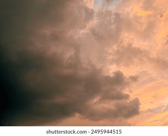 The image captures a dramatic sky during sunset. The lower part of the sky is bathed in warm orange and yellow hues, while the upper part is filled with darker clouds, suggesting an approaching storm.
