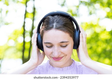 The image captures a serene moment as a young woman, adorned with headphones, enjoys her favorite melodies. Eyes closed, she appears to be lost in the harmonious embrace of music, with a gentle smile