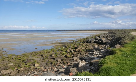 The image captures a serene and peaceful coastline with a rocky shore, calm waters, and a vast open sky overhead, evoking a sense of tranquility and wonder at nature's beauty. - Powered by Shutterstock