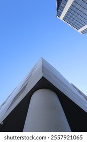The image captures the sharp angle of a building's corner, its clean lines meeting the expansive sky. The corner of the building juts out , with the architectural details subtly fading
