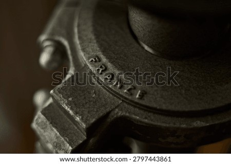  The image captures a tight horizontal macro perspective of a heavy industrial or mechanical part. The razor-sharp focus cuts across the curved metallic ridge, highlighting the raw, granular texture of the cast iron surface and the clean, stamped sans-serif typography reading 