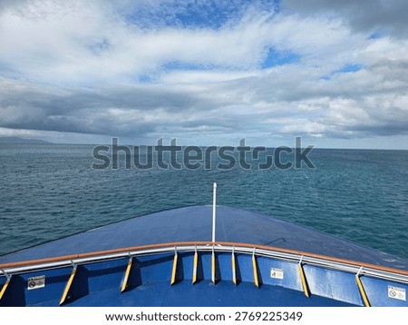 The image captures the view from the bow of a ship heading towards the open ocean under a cloudy sky. This scene is ideal for use in travel brochures and nautical-themed articles.