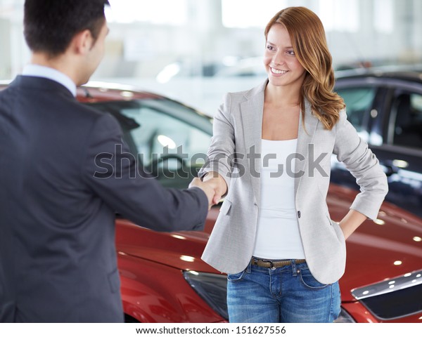 Image of car dealer handshaking with happy female
in automobile center