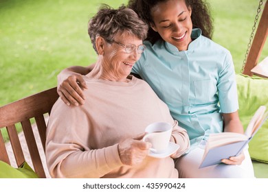 Image Of Caregiver And Senior Resting In The Garden