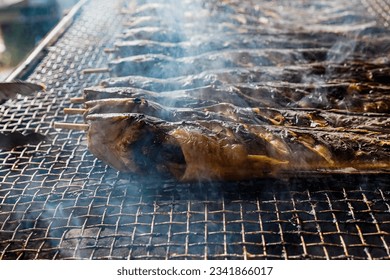 The image of the catfish grilled on the stove, wafting in smoke, in dark lighting is an art. - Shutterstock ID 2341866017