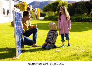 Image Of Caucasian Father Showing Solar Panel To Children. Family, Green Energy, Eco Awareness And Spending Quality Time Together Concept.