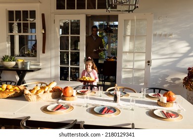 Image of caucasian girl preparing outdoor dinner on patio. Childhood, responsibilities and helping at home concept.
