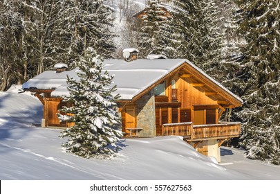 Image of a chalet located in a forest covered in snow.