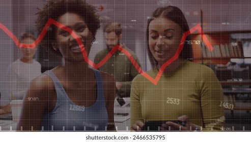 Image of changing numbers and red graph against two diverse women discussing at office. Computer interface and business data technology concept