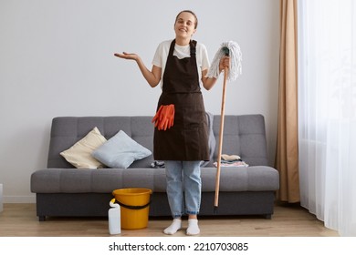 Image Of Charming Cute Smiling Female Washing Floor With Mop At Home, Cleaning Apartment With Hopeless Expression, Shrugging Shoulders, Looking At Camera With Toothy Smile.