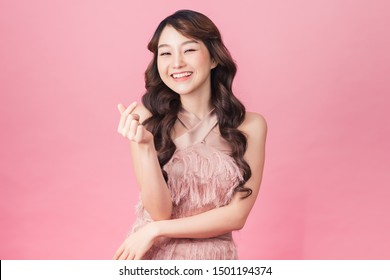Image of charming woman 20s wearing dress smiling and standing isolated over pink background